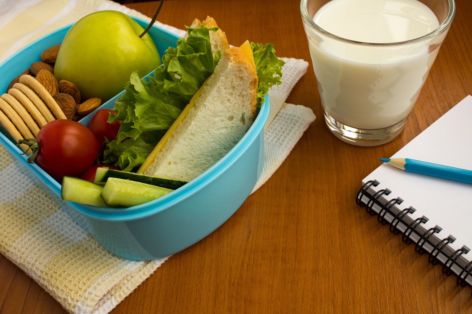 School lunch in the box, milk in the glass and notebook on the t